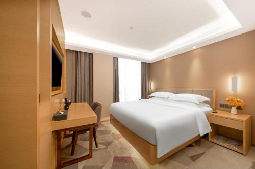 a bedroom with a large white bed and a desk at Guangzhou Baiyun Airport Yunzhi Hotel near Terminal One - Complimentary Shuttle Bus between hotel to Canton Fair Complex during Canton Fair in Guangzhou