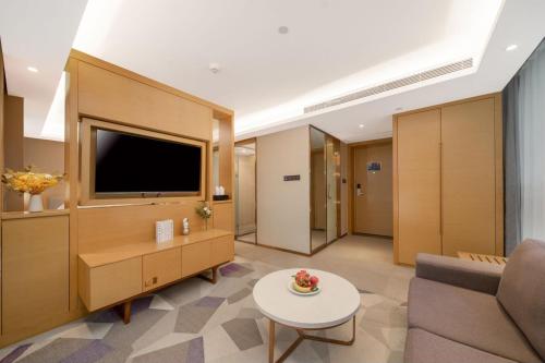 a living room with a tv and a couch and a table at Guangzhou Baiyun Airport Yunzhi Hotel near Terminal One - Complimentary Shuttle Bus between hotel to Canton Fair Complex during Canton Fair in Guangzhou