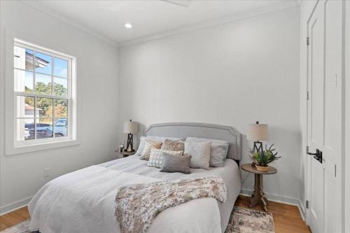 a white bedroom with a bed and a window at Chandeleur Town Home in Pass Christian