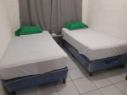 2 Betten in einem Zimmer mit grünen Kissen darauf in der Unterkunft Apartamento 33 in Santa Ana