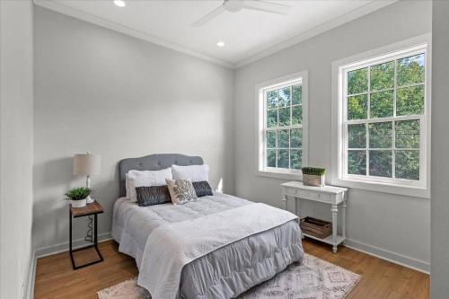 a white bedroom with a bed and two windows at Pass Marianne Town Home in Pass Christian