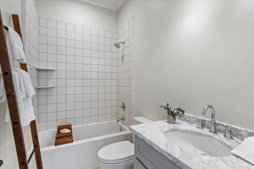 a white bathroom with a tub and a toilet and a sink at Pass Marianne Town Home in Pass Christian