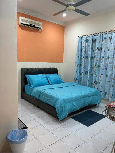 Schlafzimmer mit einem Bett mit blauer Bettwäsche und einem Ventilator in der Unterkunft Venice 142 Homestay in Lumut