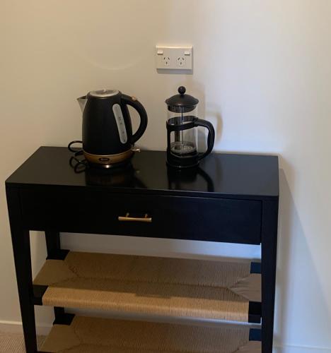 a black table with a tea pot and a kettle on it at Sun and sea at manly in Whangaparaoa
