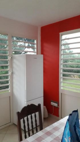 a kitchen with a white refrigerator and red walls at l'HABITATION in Le Gosier