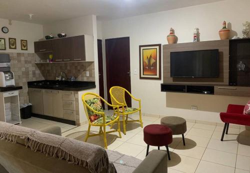 a living room with yellow chairs and a kitchen at Bela casa de praia beira mar in Feliz Deserto