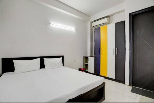 - une chambre avec un lit blanc et une porte jaune et noire dans l'établissement Ashiyana Homes, à New Delhi