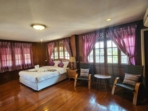 a bedroom with a bed and two chairs and a table at Malulee Homestay/Cafe/Massage in Lampang