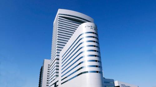 a tall white building with a blue sky in the background at Palace Hotel Omiya in Saitama