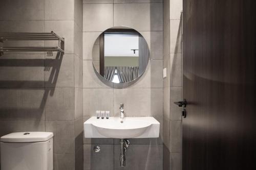 a bathroom with a sink and a mirror and a toilet at K Avenue by Pinstay in Donggongon