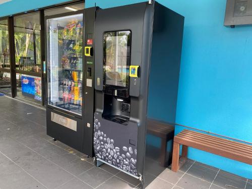 uma máquina de venda automática de bebidas ao lado de um banco ao lado de um edifício em Nobby Beach Holiday Village em Gold Coast