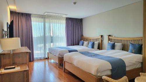 Habitación de hotel con 2 camas y ventana en IlleInn Hotel en Seogwipo