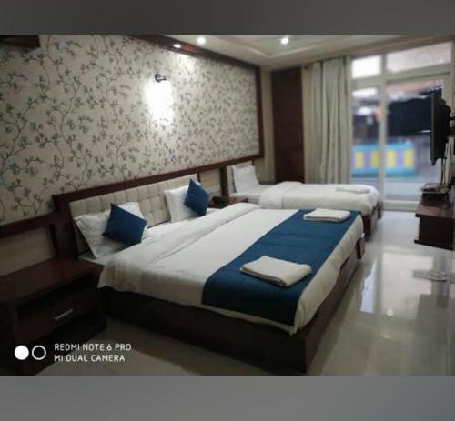 Cette chambre d'hôtel comprend 2 lits avec des oreillers bleus. dans l'établissement Royal Aryan Hotel, à Purî