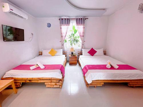 a bedroom with two beds and a tv and a window at Mui Ne Sunlight Villa in Mui Ne