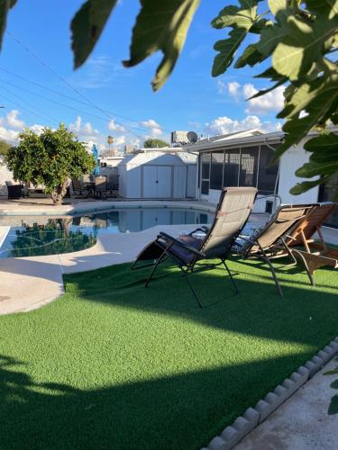 zwei Stühle auf dem Rasen in der Nähe eines Pools in der Unterkunft Cozy Home with Sparkling Pool/Pet Friendly in Mesa