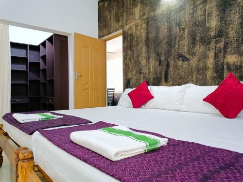1 dormitorio con 1 cama grande con almohadas rojas y blancas en Alma Homestay en Mararikulam