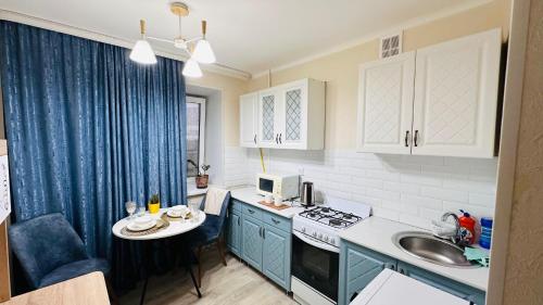 uma cozinha com armários azuis, um lavatório e uma mesa em Ардк em Oral