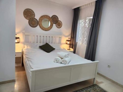 ein Schlafzimmer mit einem weißen Bett mit Handtüchern darauf in der Unterkunft Apartment Beachfront Accommodation in Estepona