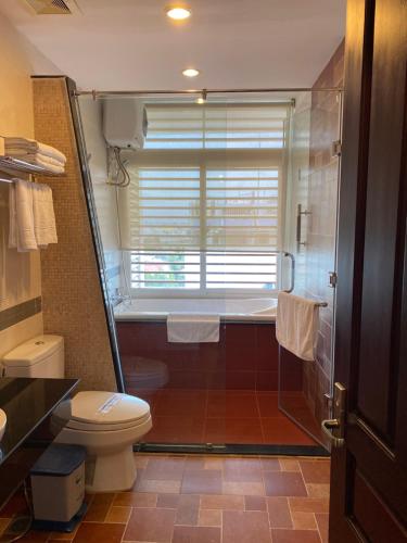 a bathroom with a shower and a toilet and a window at Kim Tho Hotel in Can Tho