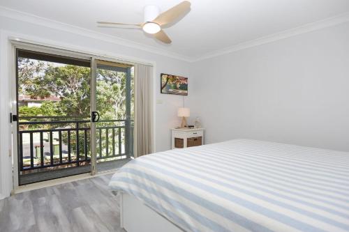 a white bedroom with a bed and a balcony at Bennett's Beach House in Hawks Nest