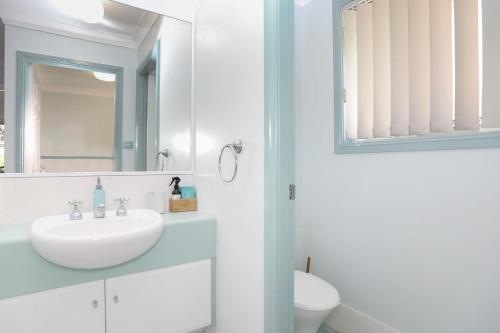 a white bathroom with a sink and a mirror at Bennett's Beach House in Hawks Nest