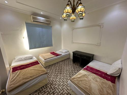 a room with three beds and a window and a chandelier at Al Badeel Hotel in Al Madinah