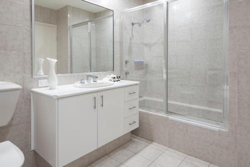 a white bathroom with a shower and a sink at Poinciana Lodge - 2 bedroom - on Hamilton Island by HIHA in Hamilton Island