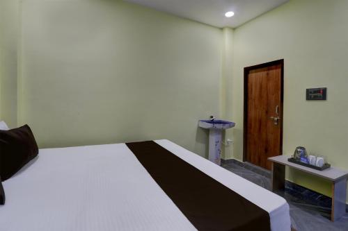 1 dormitorio con 1 cama blanca grande y puerta de madera en OYO Flagship SRI JOGULAMBA RESIDENCY, en Bālānagar
