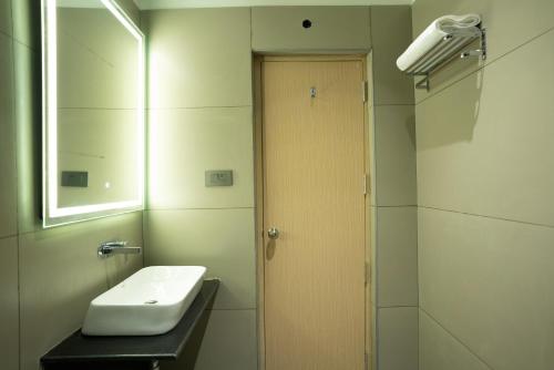 a bathroom with a sink and a wooden door at Hotel Kyzen Hi Tech City in Hyderabad