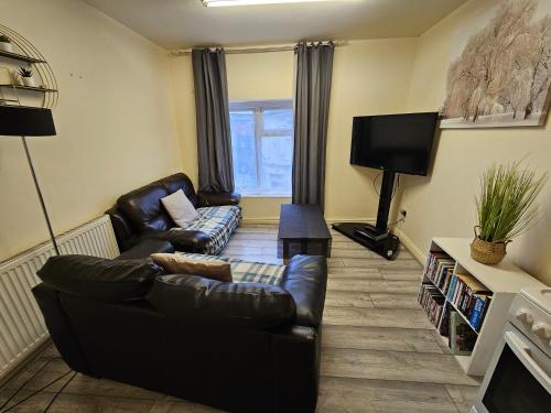 a living room with a leather couch and a tv at 2 bedroom apartment in Greater Manchester in Ashton under Lyne