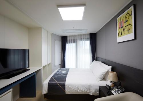 a hotel room with a bed and a television at Sokcho Chonpines Beach Hotel in Sokcho