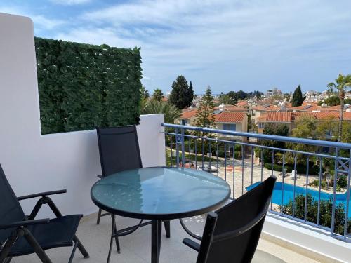 eine Terrasse mit einem Glastisch und Stühlen auf dem Balkon in der Unterkunft Paradise Gardens 1 in Paphos City