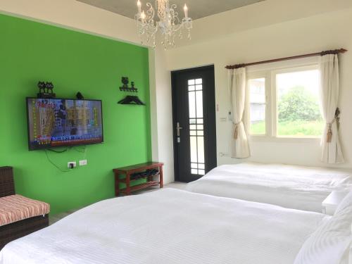a green bedroom with two beds and a television on the wall at 稻哪趣田園民宿 平價villa in Dongshan