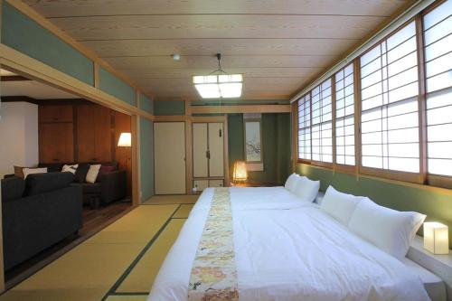 a large white bed in a room with windows at bHOTEL Kaniwasou 301 Minute walk from Miyajima Pier for 11ppl in Miyajima