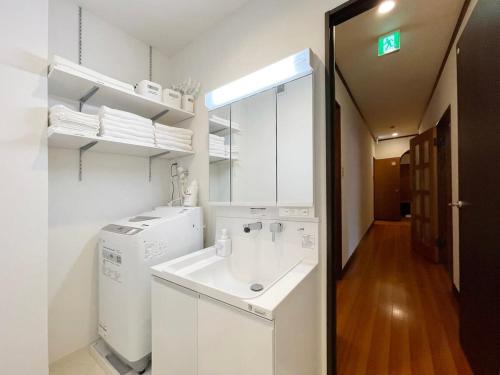 a white bathroom with a sink and a mirror at bHOTEL Kaniwasou 301 Minute walk from Miyajima Pier for 11ppl in Miyajima