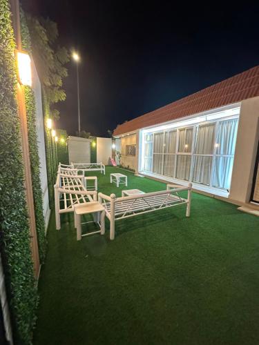 un patio con 2 bancos en el césped por la noche en شاليه هاشتاق الودي, en Al Wudayy