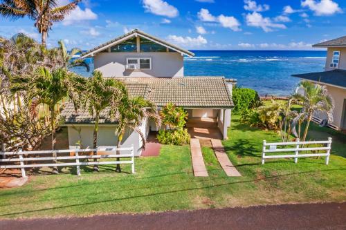 a white house with the ocean in the background at Kauai Aliomanu home in Anahola
