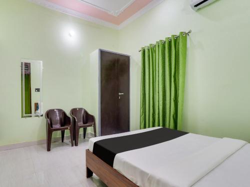 a bedroom with a bed and a chair and green curtains at OYO Shri Radhe Guest House & Restaurant in Rishīkesh