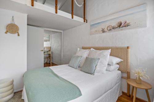 Chic 2-Bed Cabin-Style Home by Mooloolaba Beach في مولولابا: غرفة نوم بسرير ذو شراشف بيضاء ومخدات زرقاء