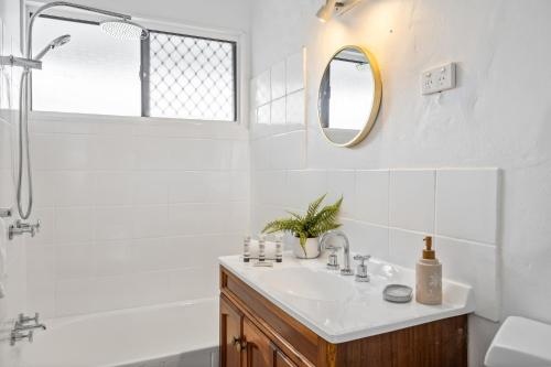 a white bathroom with a sink and a mirror at Chic 2-Bed Cabin-Style Home by Mooloolaba Beach in Mooloolaba