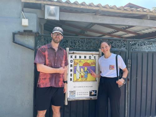 a man and a woman standing next to a sign at Kenno's Korner in Weligama