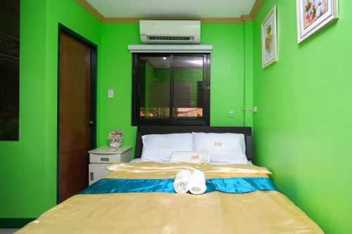 a green room with a bed with two white shoes at Golden V Primera Unit B in Malolos