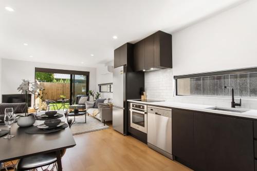 a kitchen and living room with a table and a counter top at Stylish New 8 Mins CBD Free Parking in Christchurch