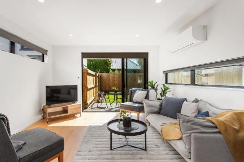 a living room with a couch and a tv at Stylish New 8 Mins CBD Free Parking in Christchurch