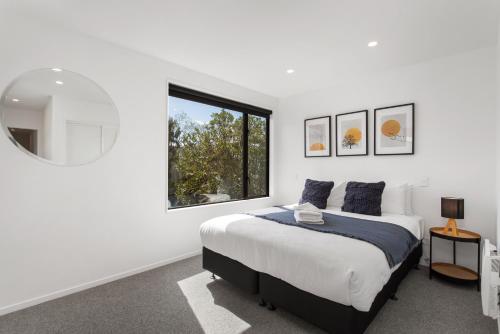 a white bedroom with a bed and a window at Stylish New 8 Mins CBD Free Parking in Christchurch