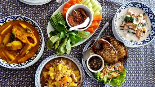a table with plates of food and bowls of food at Naiyang Beach Hotel SHA Plus in Nai Yang Beach