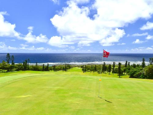 a golf course with a red flag on a green field at Hotel Shigira Mirage Beach Front in Miyako Island