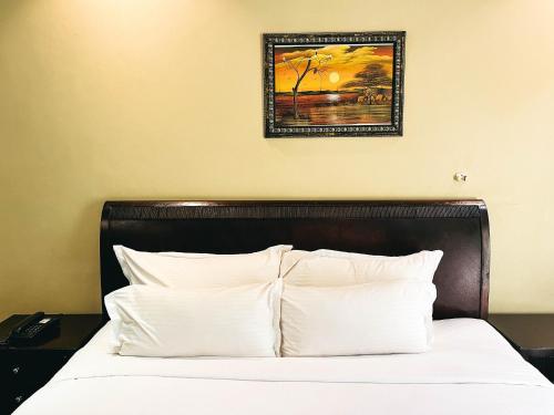 a bed with white pillows and a picture on the wall at Mafumu Hotel in Lilongwe