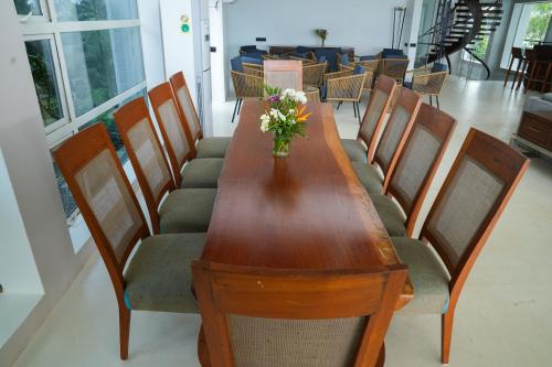 a wooden table with chairs and a vase of flowers on it at Regenta Beach House Resort, Goa in Benaulim