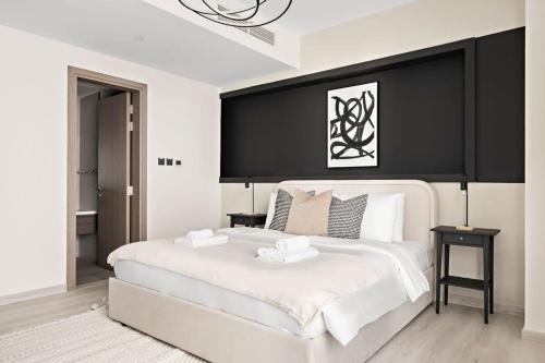 a bedroom with a large white bed with a black headboard at Silkhaus Modern 1BDR by Emirates Tower Metro in Dubai